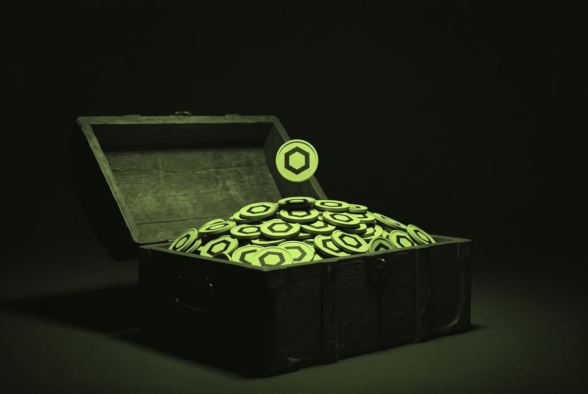 An open wooden chest piled high with coins bearing the Chainlink mark, with one more coin falling onto the heap against a dark background.